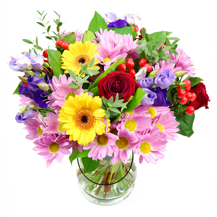 A generously proportioned floral arrangement rises from a clear glass vase, its colours intensified by the simple white background that frames the scene. At the heart of the bouquet, deep red roses draw immediate attention, their velvety petals layered in lush spirals that suggest tenderness and enduring affection. Just to one side, two bright yellow gerbera daisies with distinct dark brown-orange centres add a lively, contemporary energy, their round, open faces giving the bouquet a welcoming character. Surrounding these focal blooms is an abundance of soft pink daisies or chrysanthemums, each small flower composed of many fine petals around a tiny yellow centre, creating a soft, cushion-like halo that makes the bouquet appear full and embracing. Interwoven through the pink and red are graceful purple and lavender lisianthus, their slightly ruffled, bell-shaped blossoms adding cool contrast and an elegant, almost whimsical touch, not unlike the floral borders you might stroll past near Dulwich Picture Gallery. Bright red hypericum berries peek out between petals, their glossy, rounded forms catching the light and bringing playful texture that contrasts with the softness of the blooms. A varied selection of greenery completes the design: broad, darker leaves provide structure and depth, while slender, light-green stems and sprigs introduce freshness and a sense of movement, as if the bouquet had just been gently turned. The clear vase reveals a tidy network of stems gathered in clear water, highlighting the care and skill of the local Dulwich florist who composed it. Overall, the bouquet radiates an atmosphere of warm celebration and thoughtful generosity, ideal for birthdays, congratulations, or simply brightening a calm corner of a Dulwich home with colour and delicate scent.